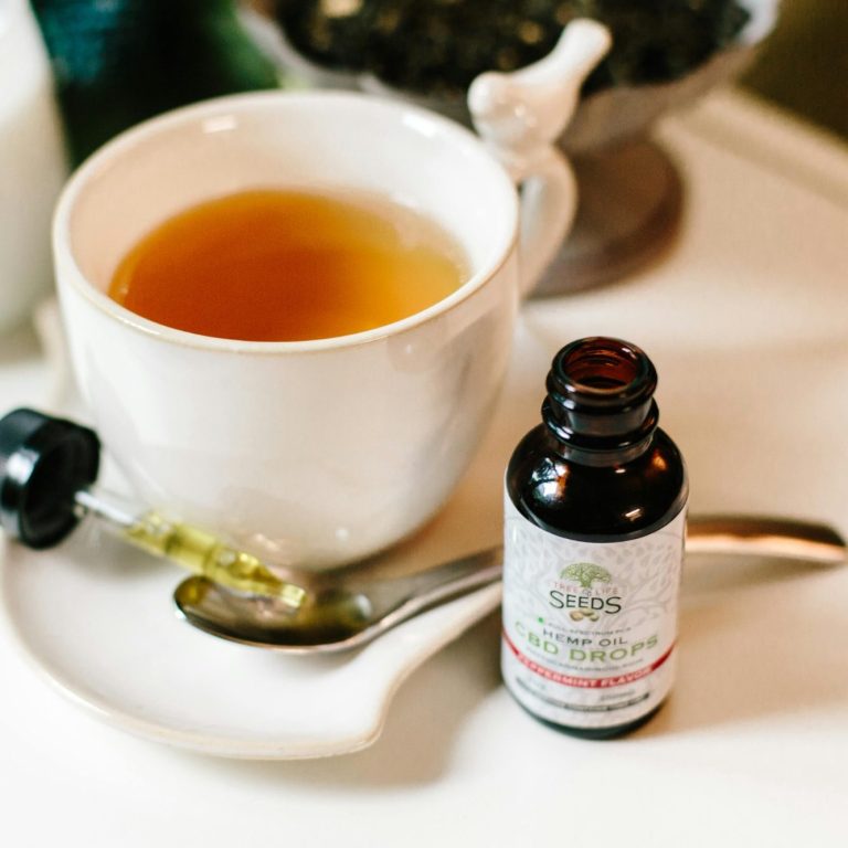 Tasse de thé avec un flacon d'huiles essentielles au CBD.